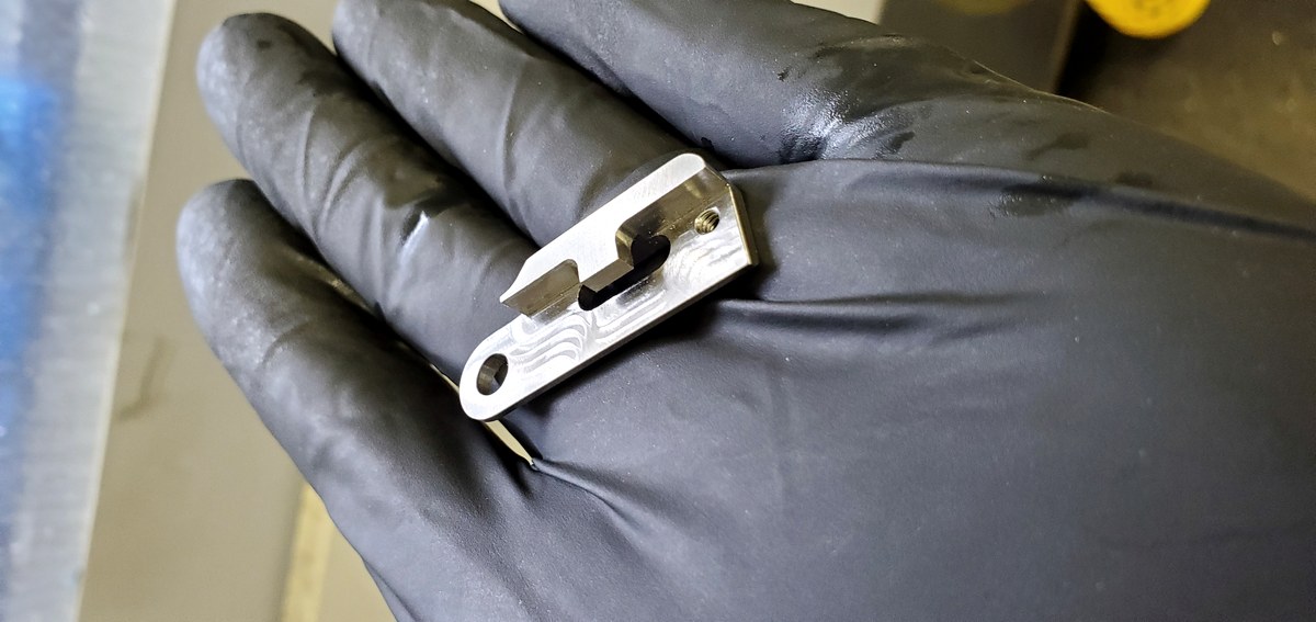 Precision machined part held in gloved hand